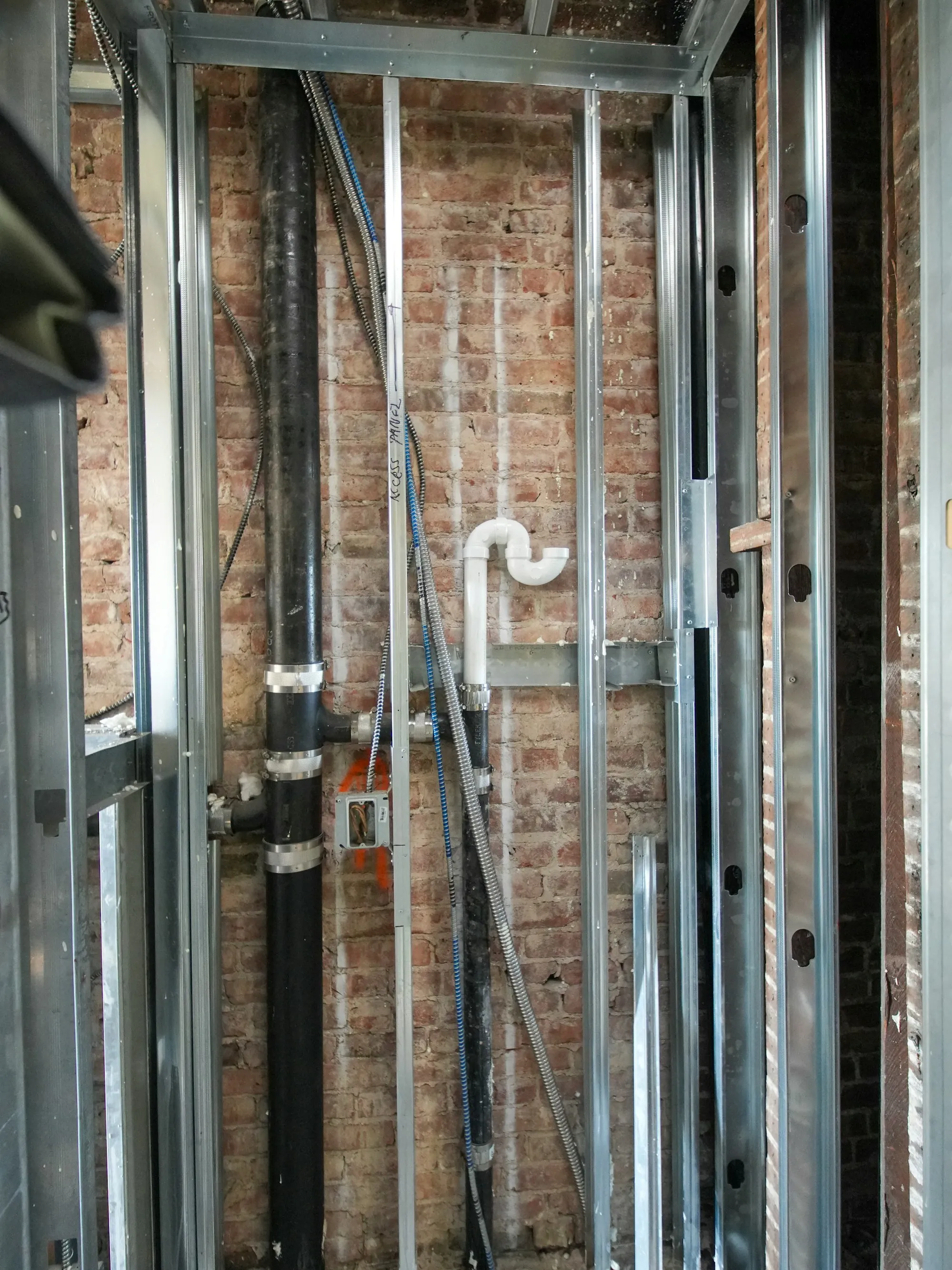 Water systems installed across Orange County Plumbing pipes and metal studs against a brick wall