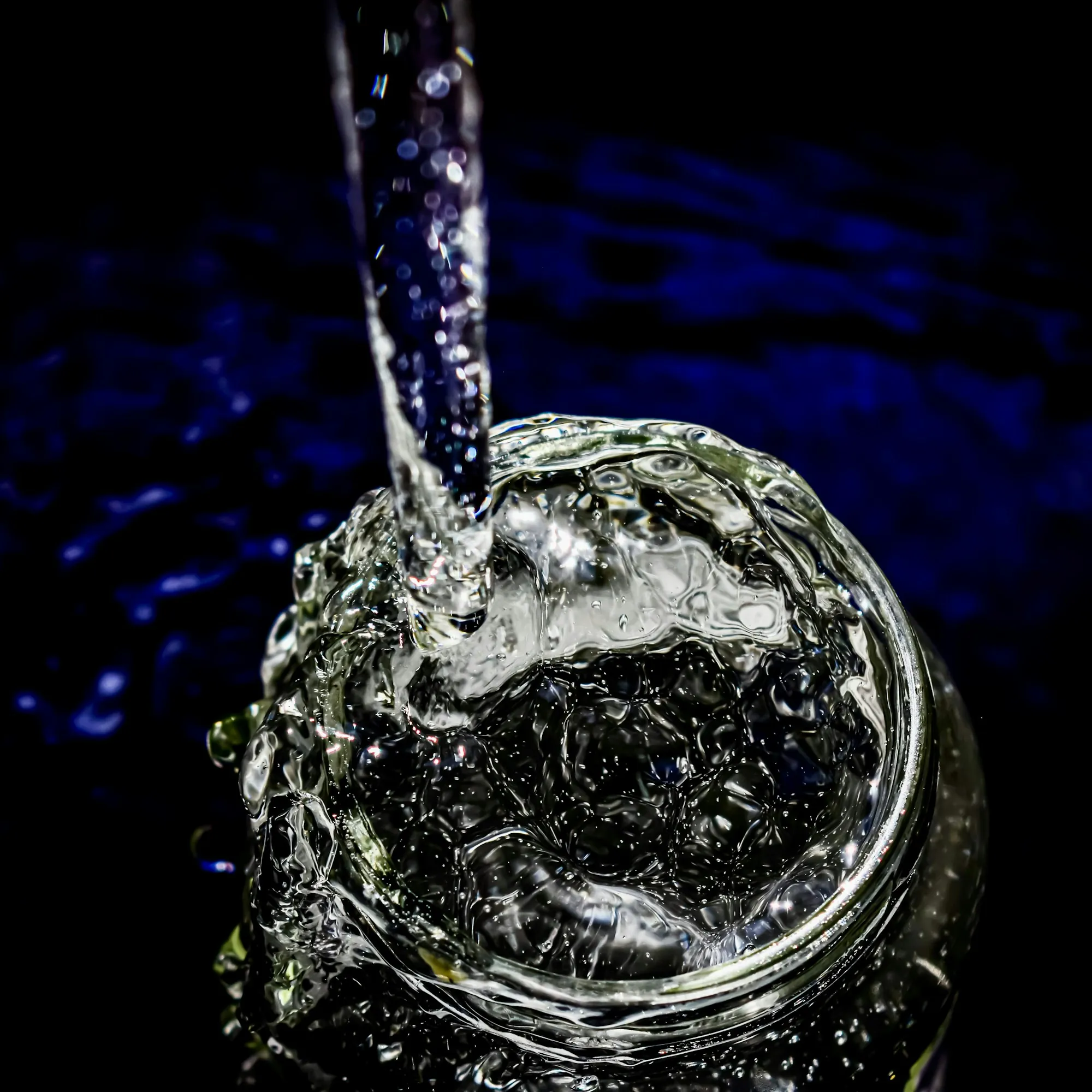 Water filtration tips for Laguna Hills homes Water pouring into a clear glass on a dark background